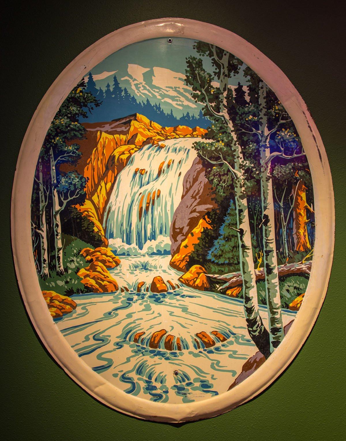 The Coors waterfall logo featured on a metal plate, a portrayal of Fish Creek Falls.